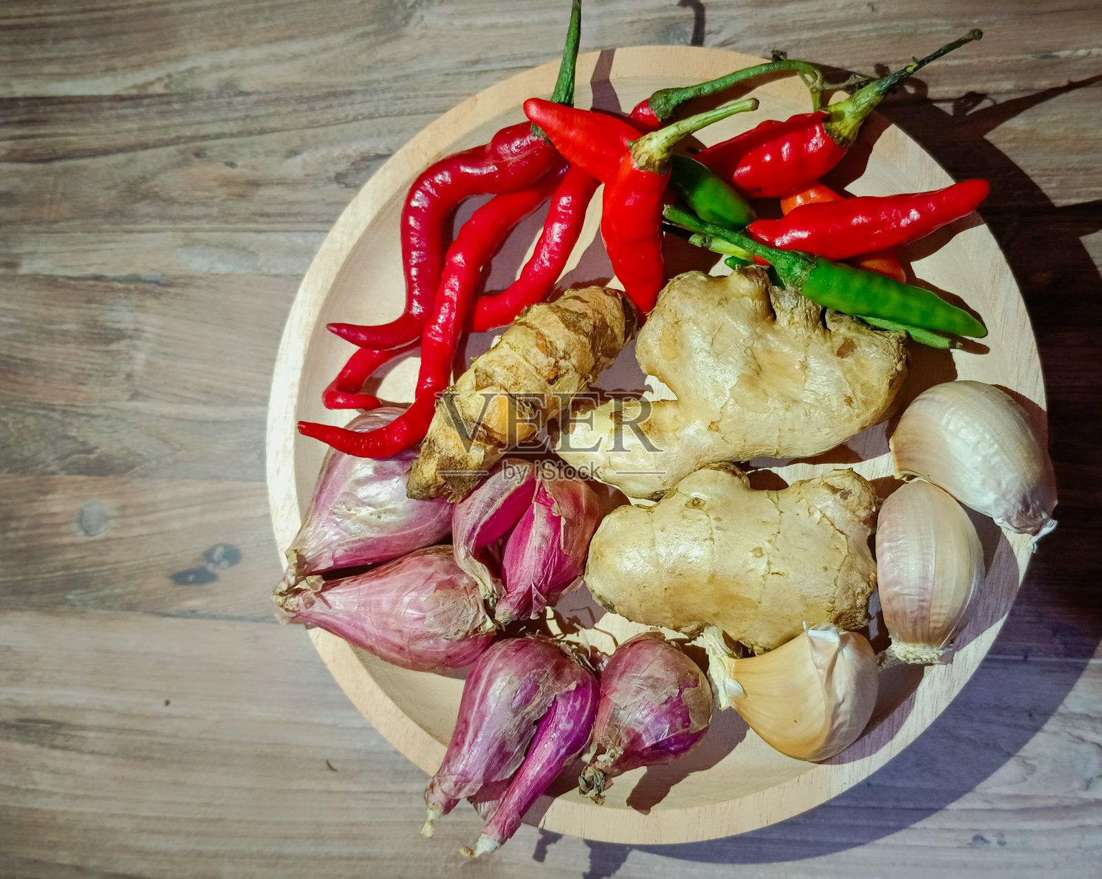 木碗上盛香料，背景为深色木碗，有姜、辣椒、青葱、大蒜、姜黄照片摄影图片