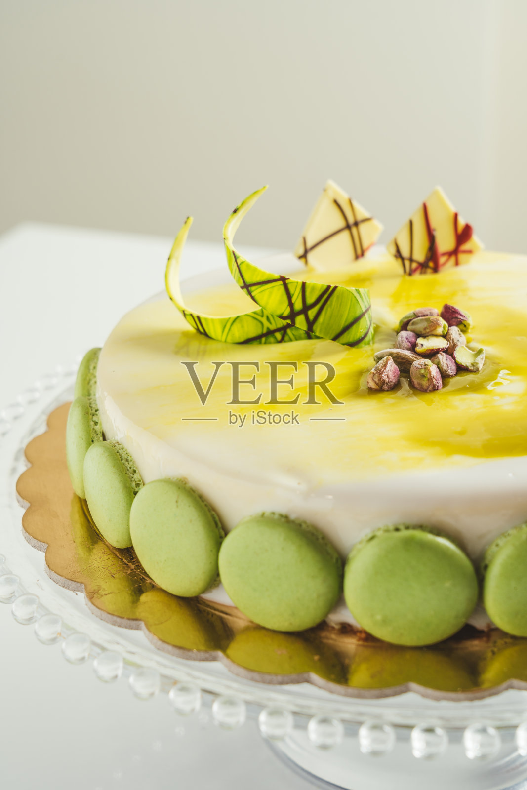 玻璃蛋糕盘上的自制白釉开心果马卡龙蛋糕照片摄影图片