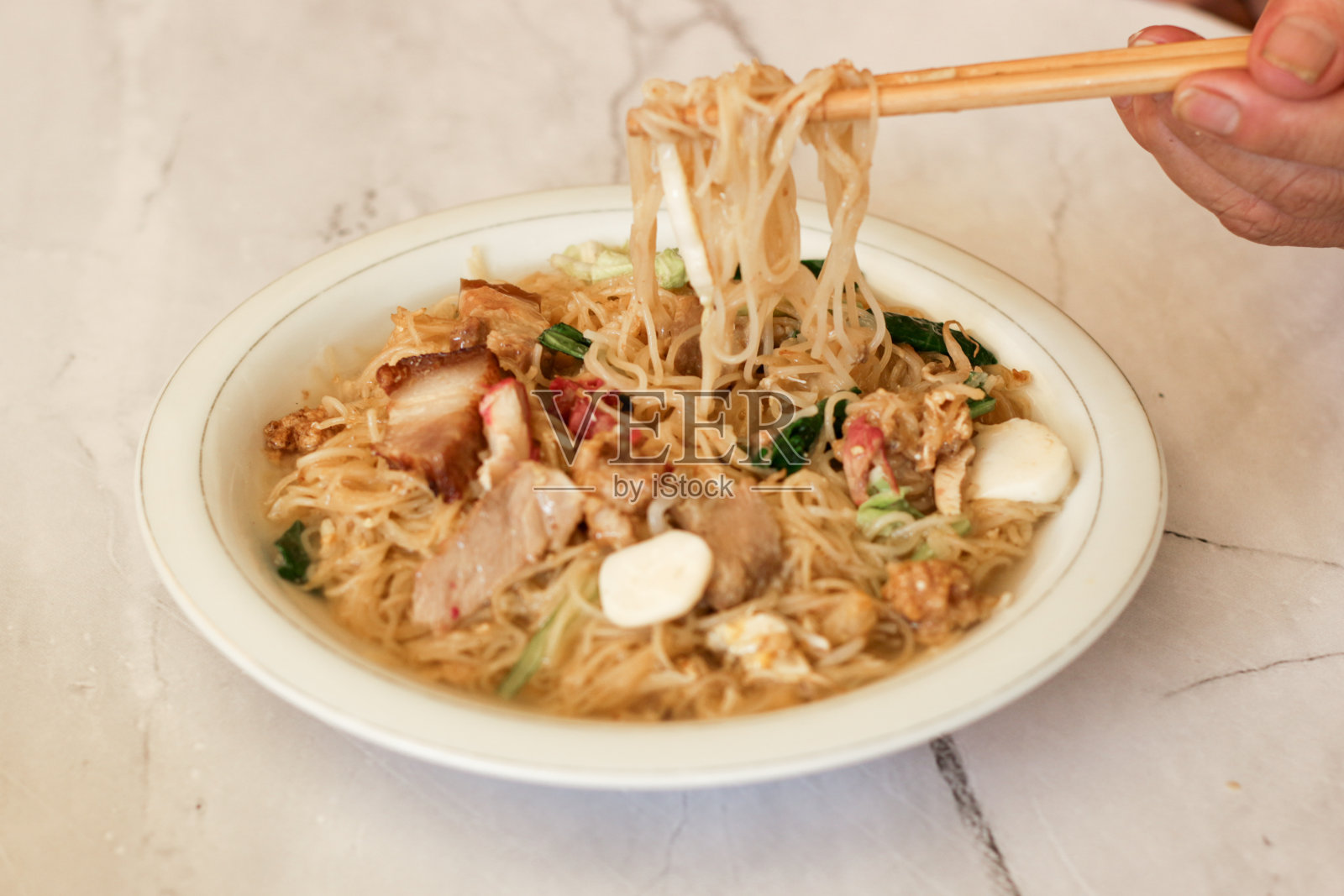 女人手里拿着筷子，拿着碗里的面条。有选择性的重点。关闭了。照片摄影图片