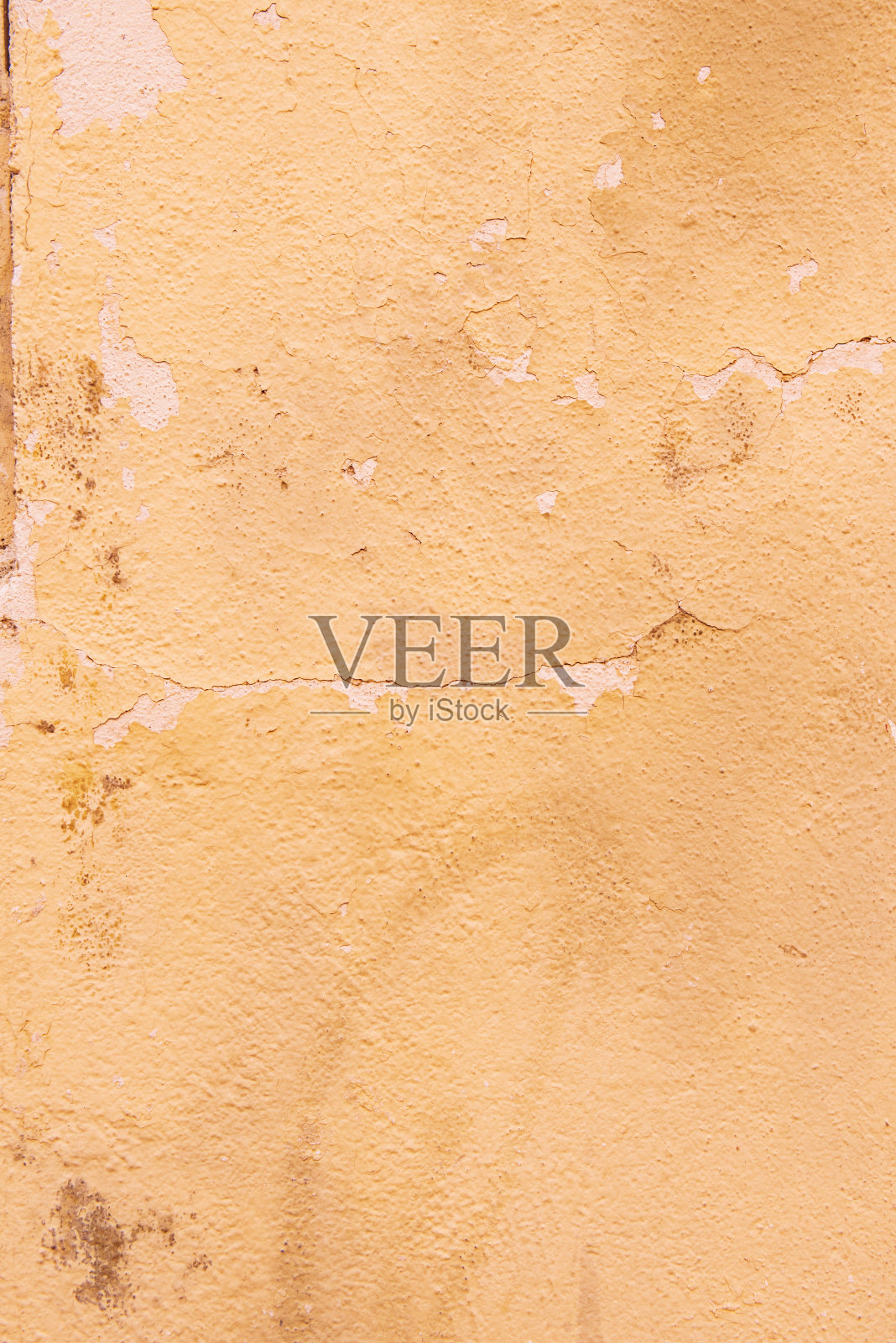 墙壁粗糙的表面，淡米黄色的油漆已经剥落照片摄影图片