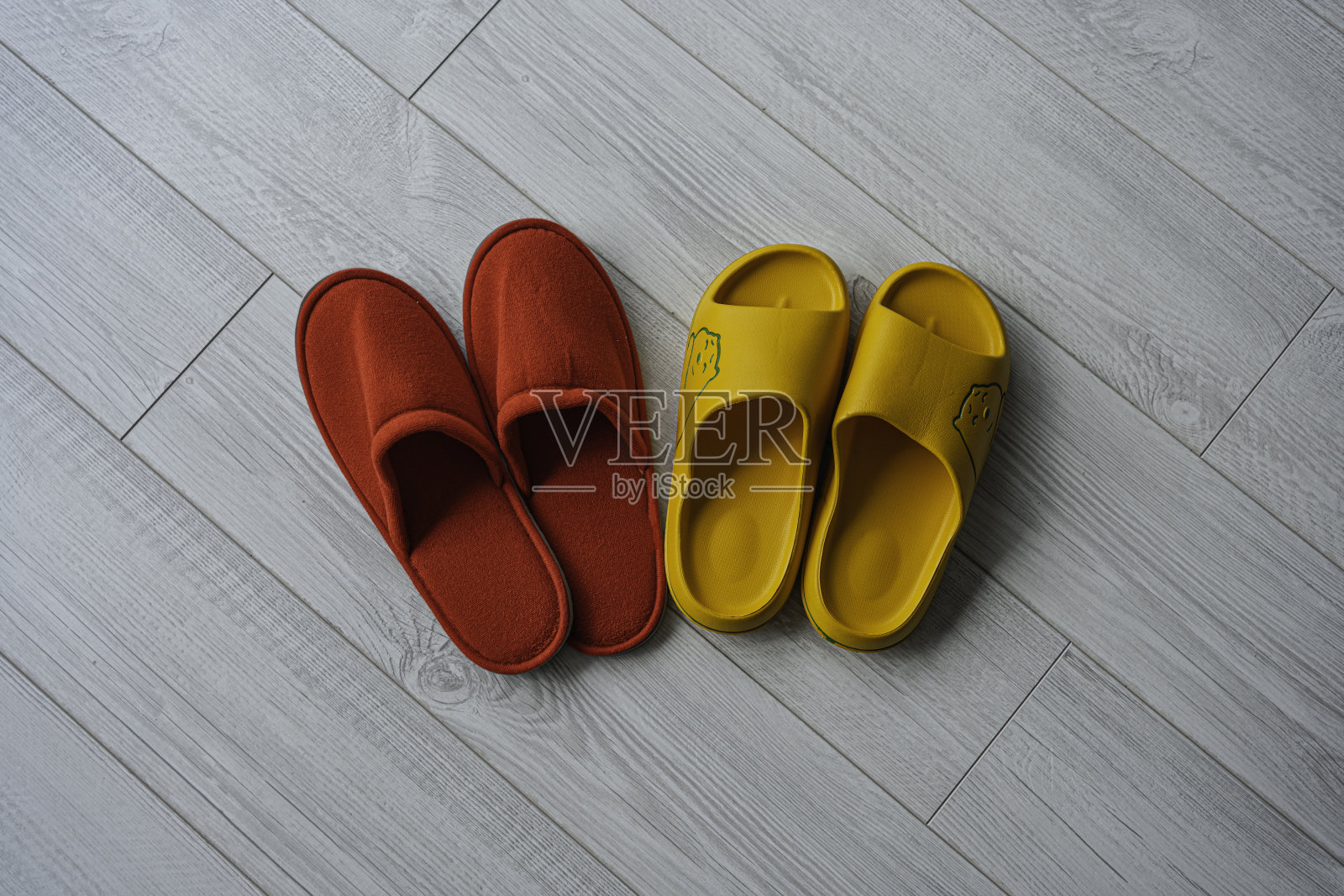 他的红拖鞋和她的黄拖鞋并排在一起。在家感觉很舒服。照片摄影图片