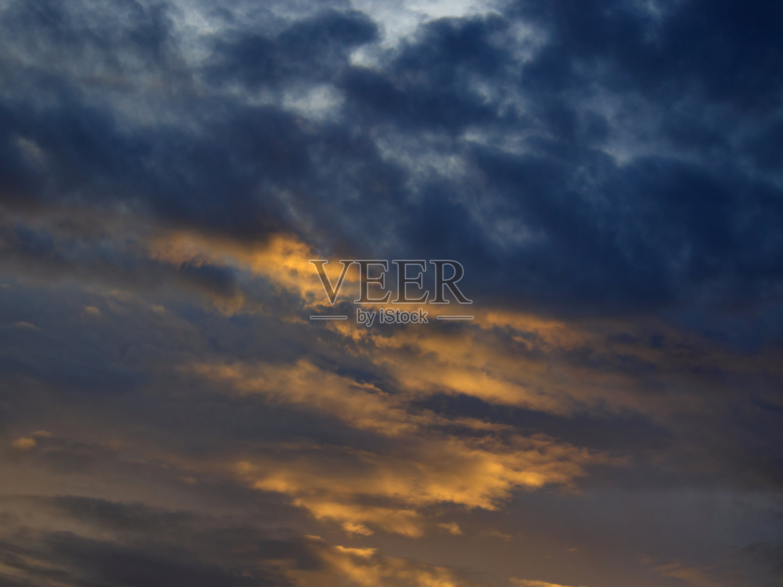 灰色的云被暮色笼罩成金色。照片摄影图片