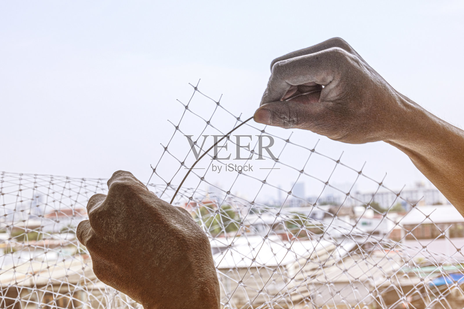 技术工人在阳台公寓安装带钢丝的保护鸽子鸟的塑料网。专业服务人员设置网鸟清洁卫生。照片摄影图片