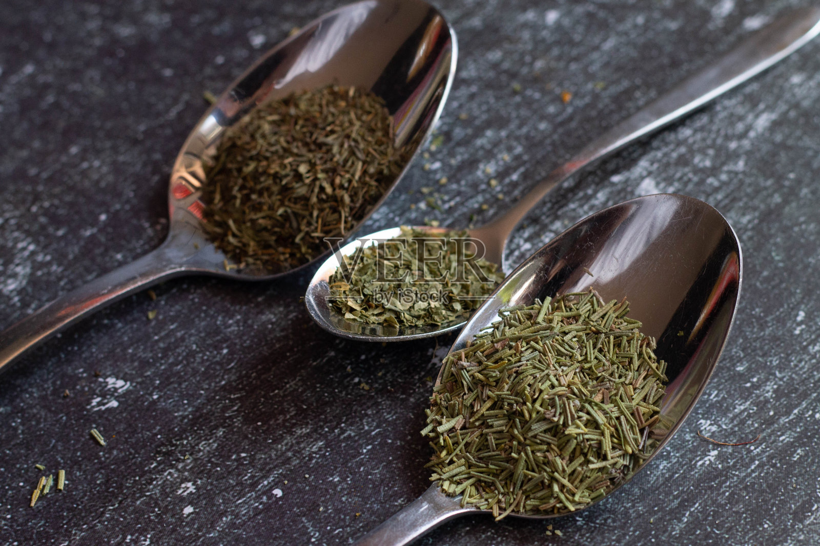 黑色背景上盛有香料和香草的勺子。食品和烹饪材料。照片摄影图片