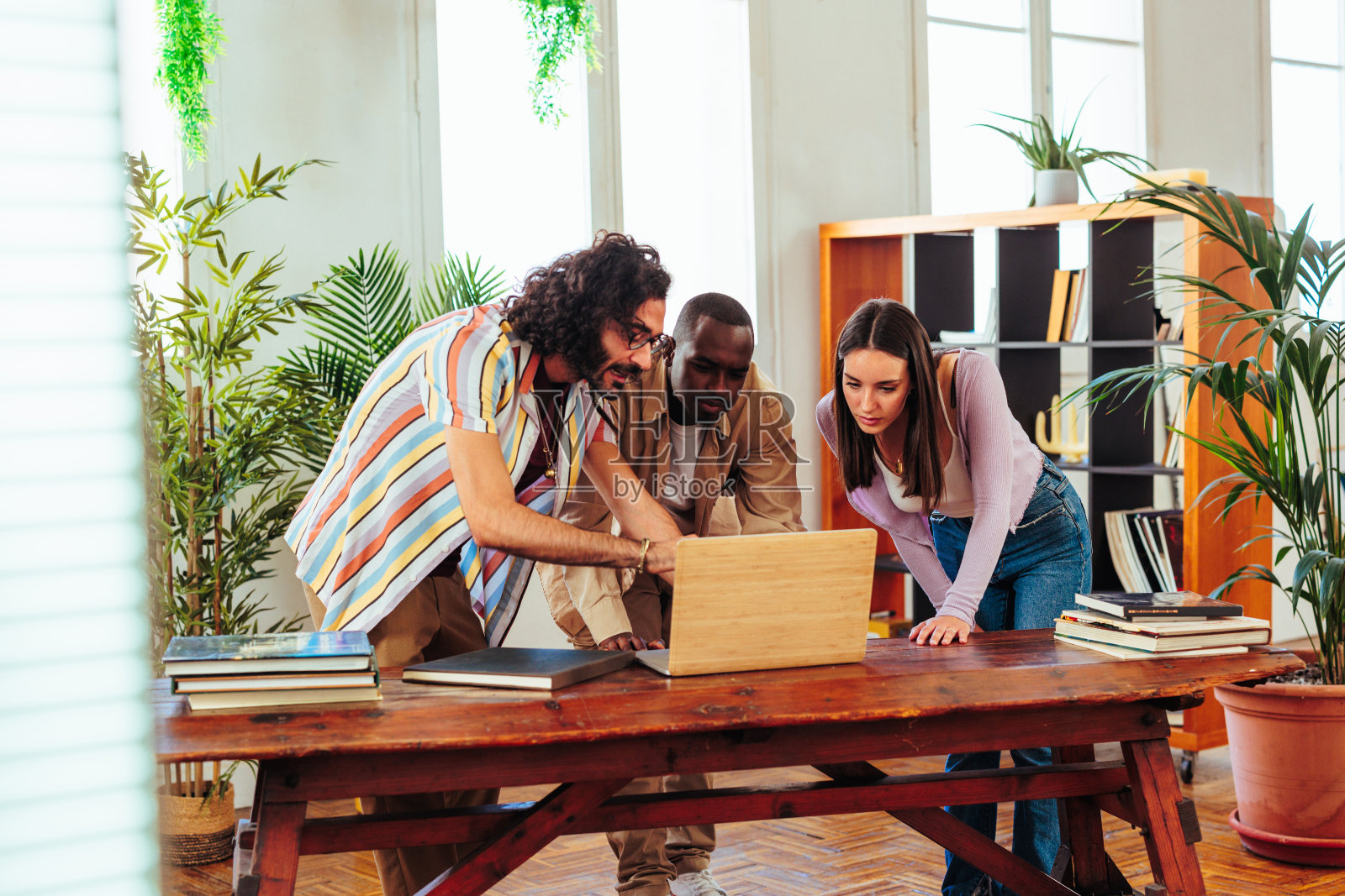三个不同种族的成年人一起使用笔记本电脑。照片摄影图片