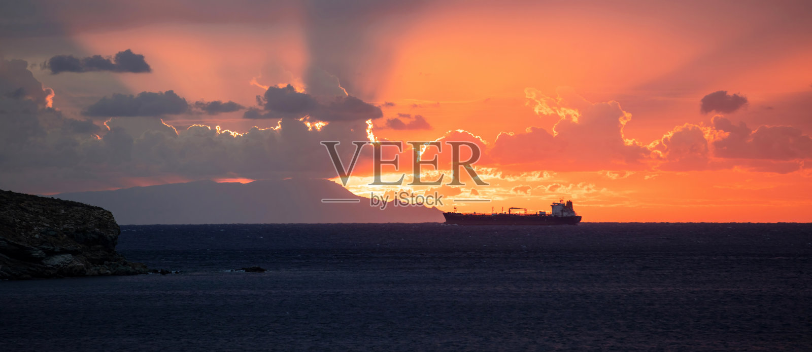 希腊基克拉迪群岛的日落。五彩的天空云廓线船深蓝色的大海。横幅照片摄影图片