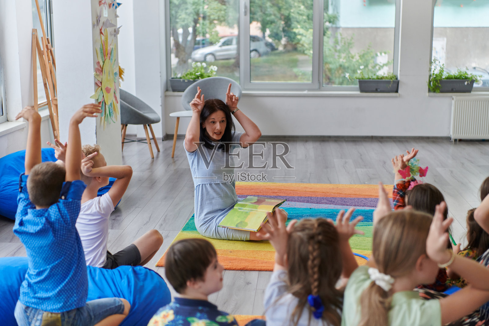 一位快乐的女老师和一群小学生坐在一起玩手游照片摄影图片