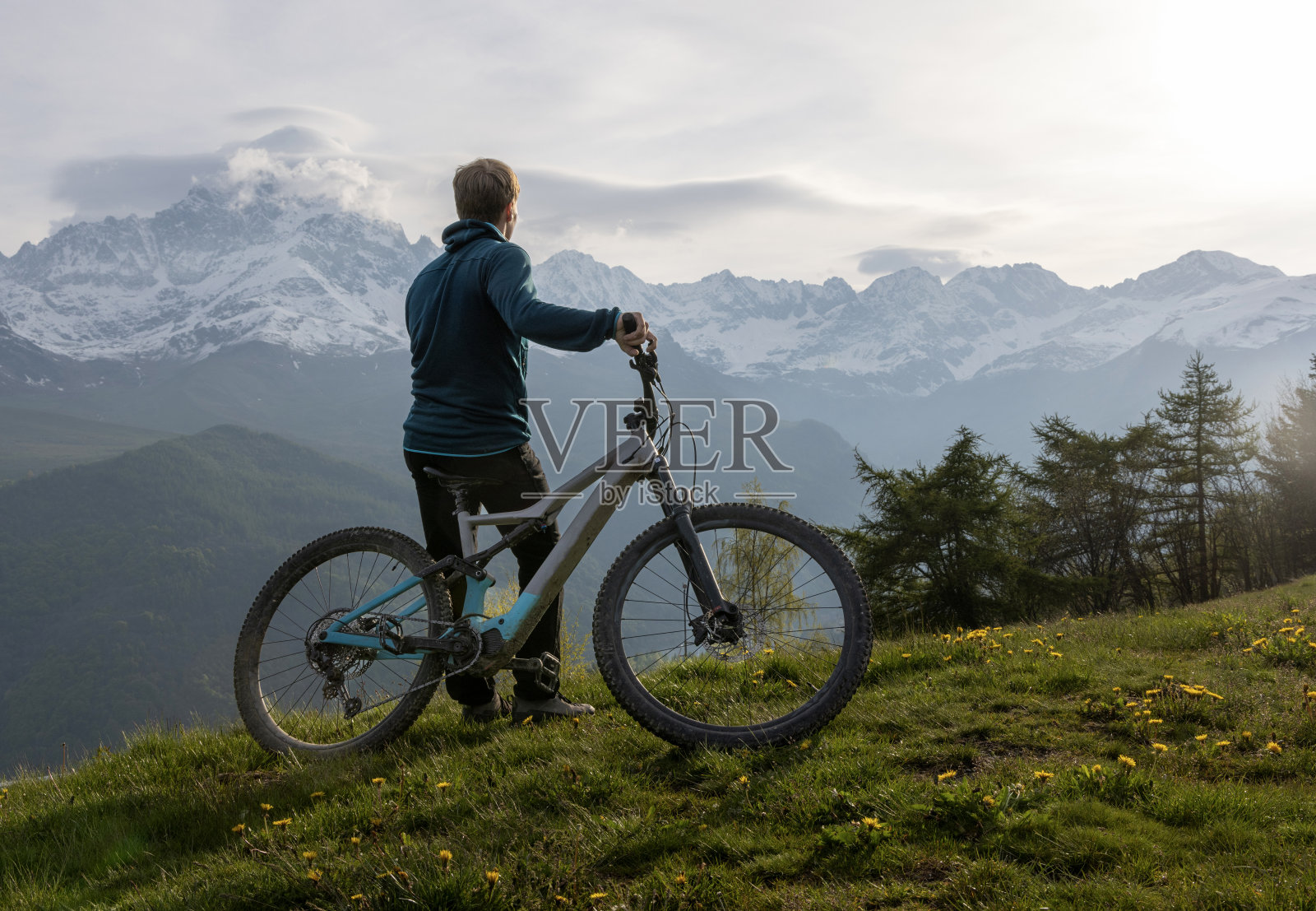 一个年轻人骑着电动自行车停在山间草地上照片摄影图片