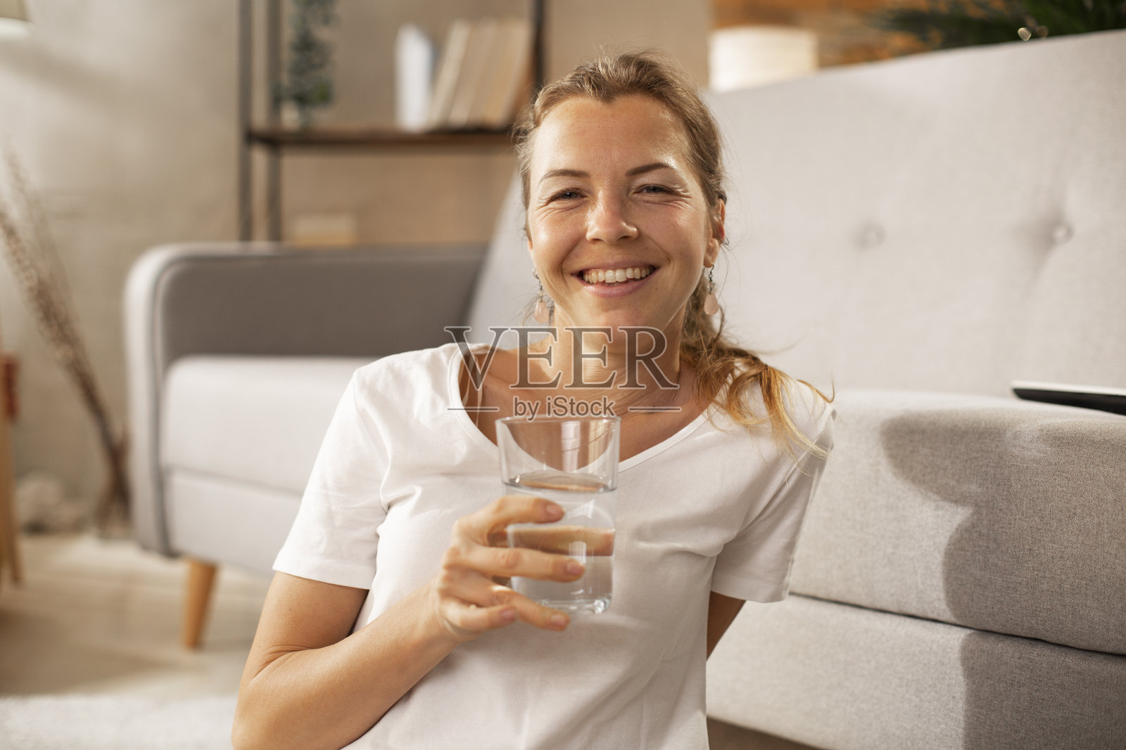 微笑的女人在喝水。照片摄影图片