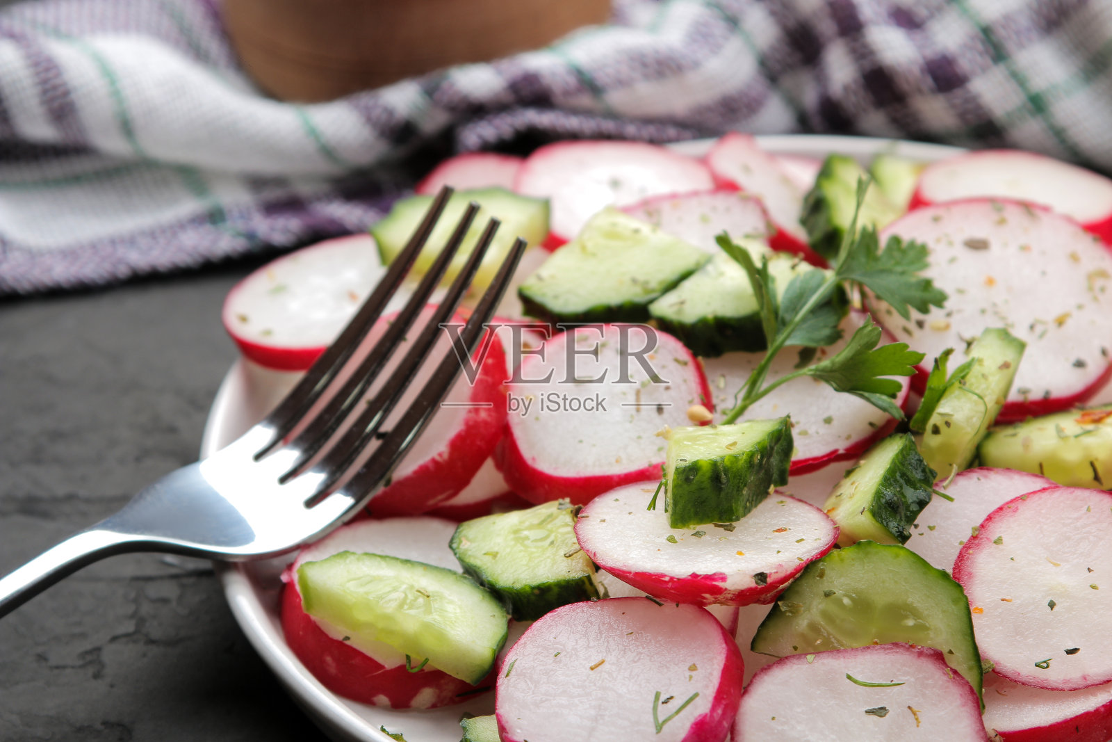 新鲜的萝卜、黄瓜沙拉和蔬菜放在黑色的混凝土桌子上。春天的蔬菜沙拉。做沙拉的原料。照片摄影图片