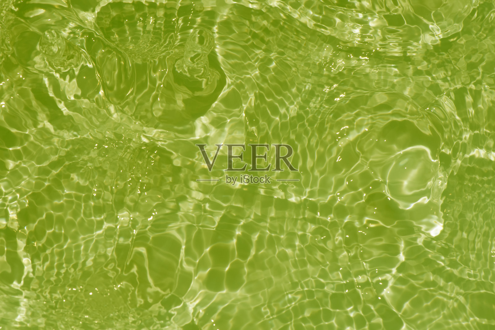 浅绿色的水面上泛起涟漪。散焦模糊透明彩色清晰平静水面纹理飞溅和泡沫。水波与闪亮的图案纹理背景。照片摄影图片