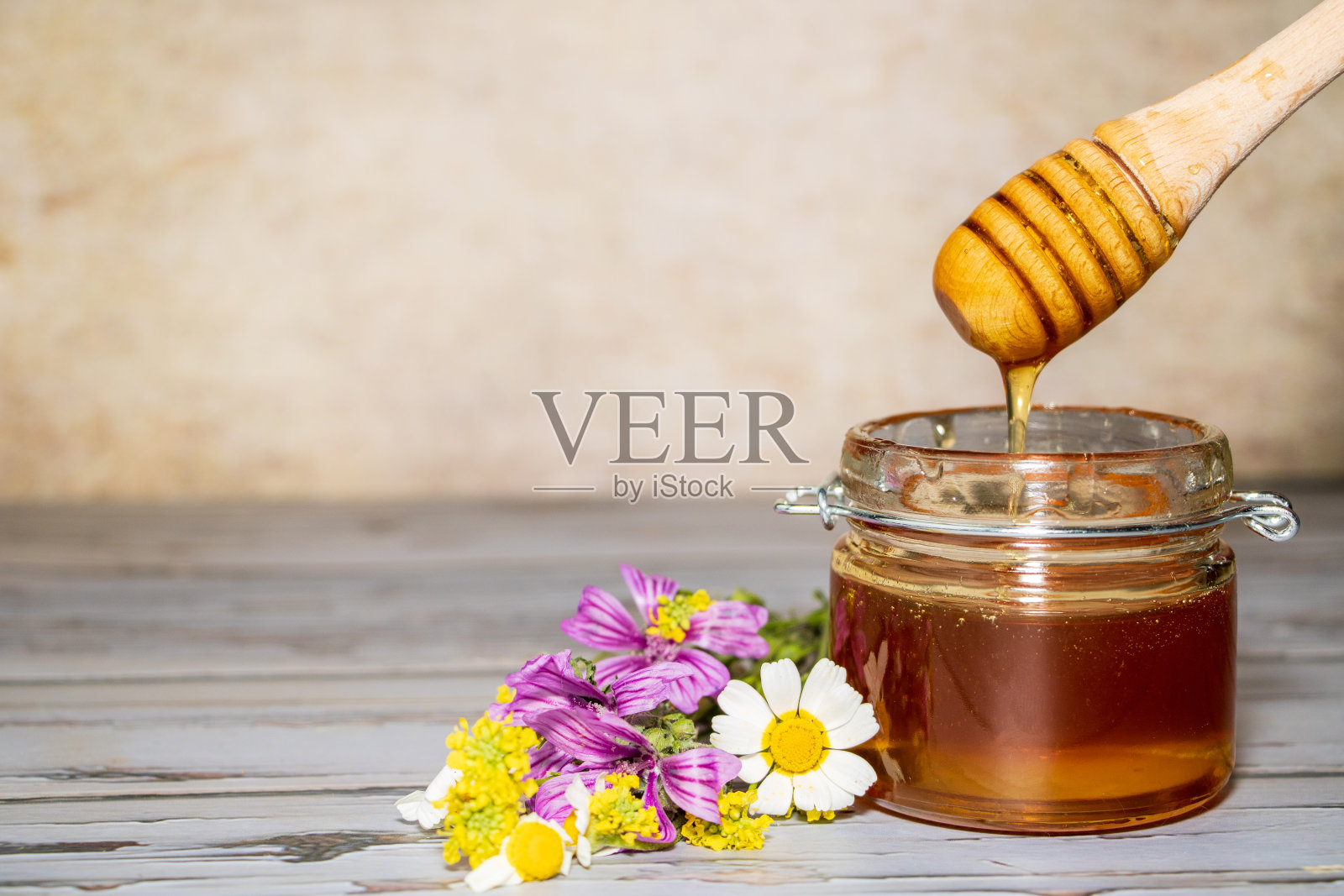 蜂蜜罐和蜜罐旁边的一些花照片摄影图片