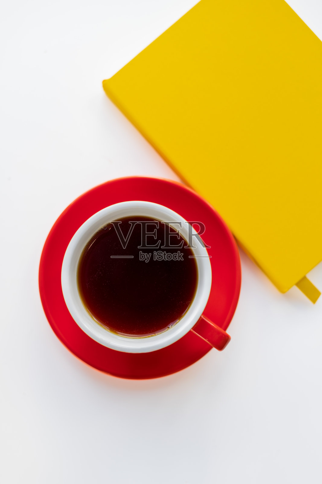 一个红色茶杯和一个黄色笔记本的俯视图。照片摄影图片