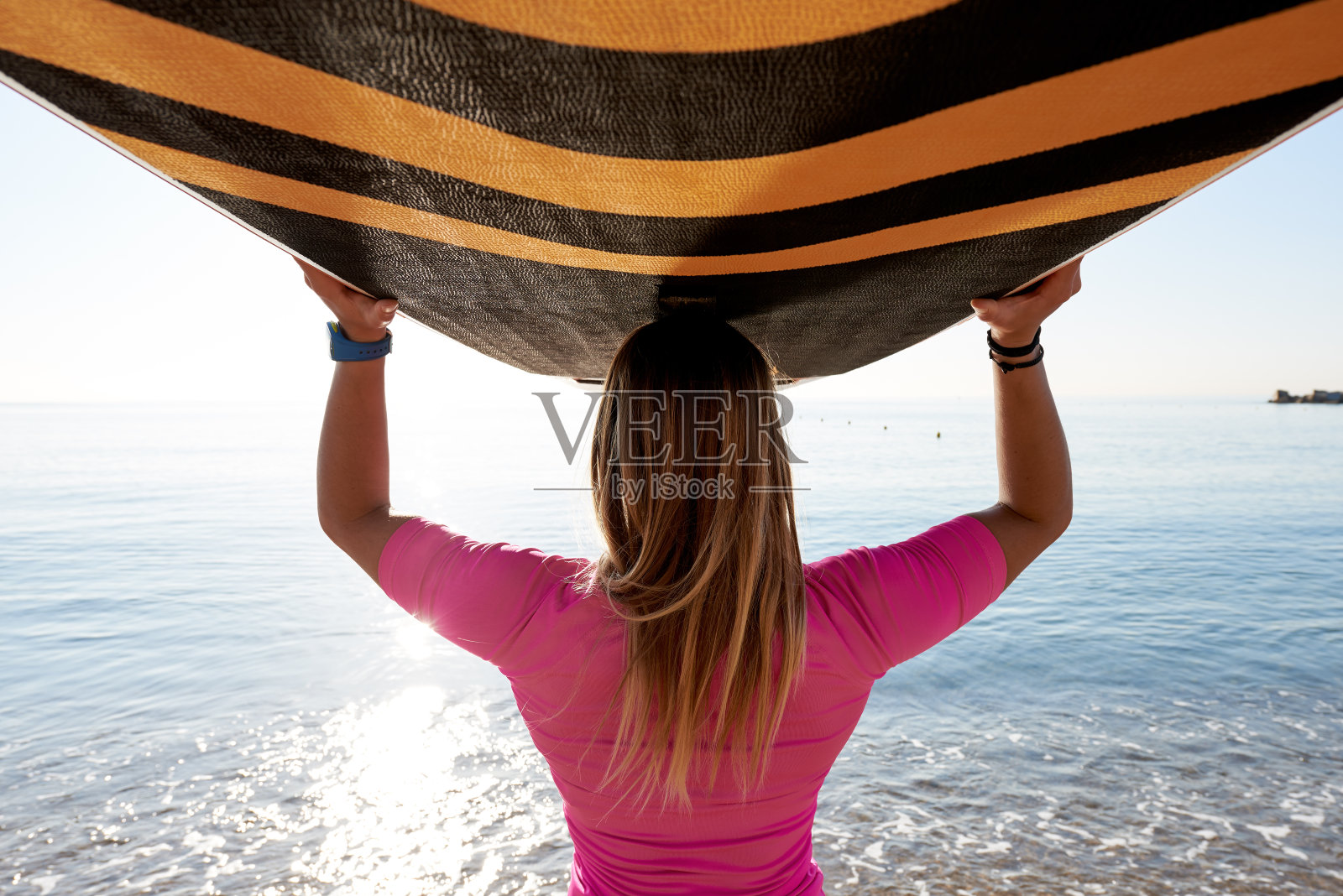 身穿粉色衣服的女运动员手持冲浪板的后视图照片摄影图片