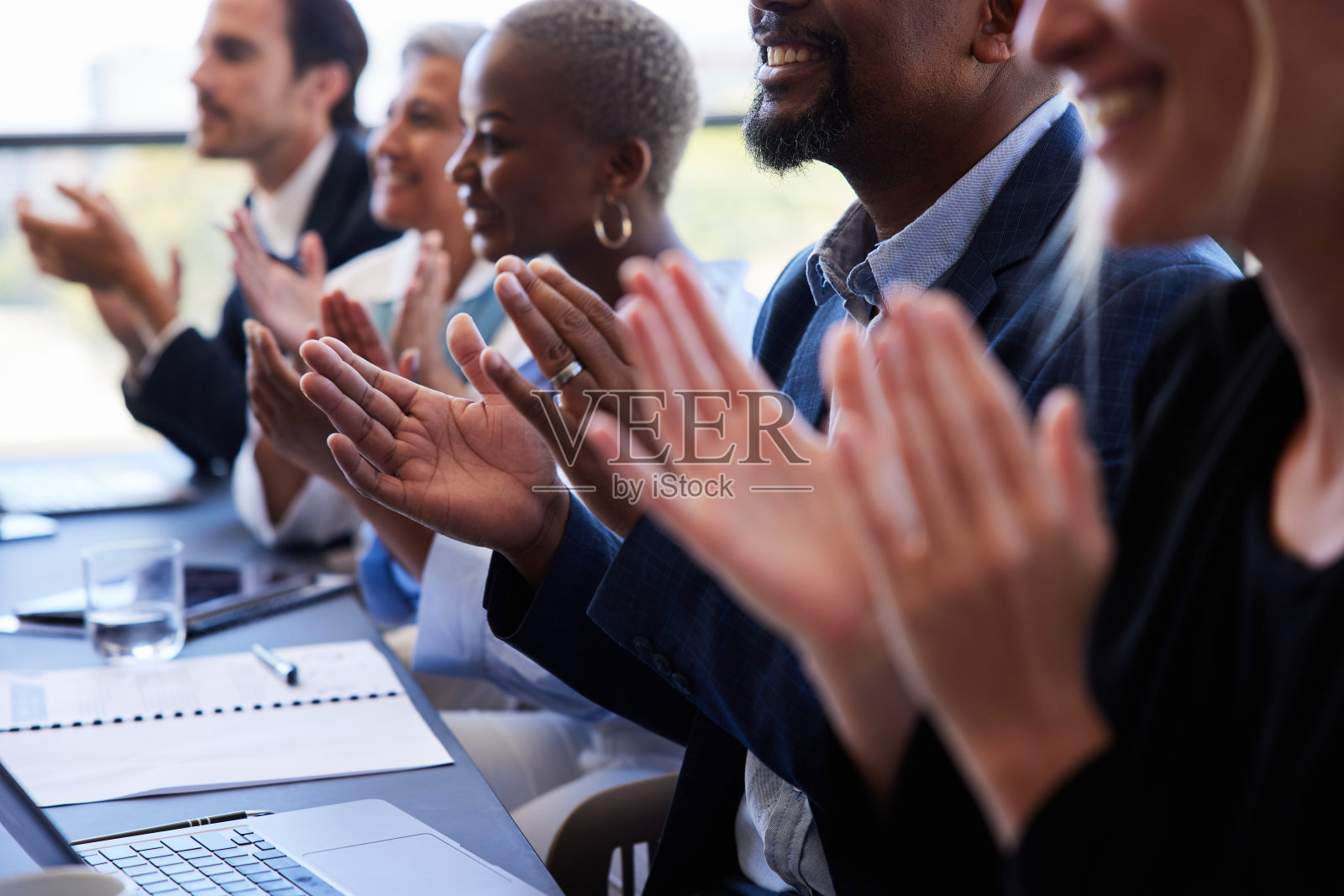 形形色色的商界人士坐在会议室的桌子旁鼓掌照片摄影图片