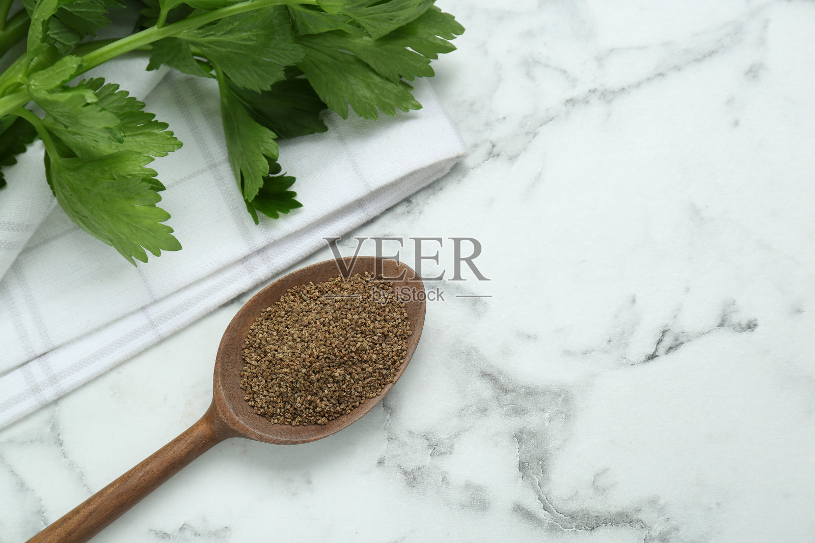 一勺芹菜籽放在白色大理石桌上，平放。文本空间照片摄影图片