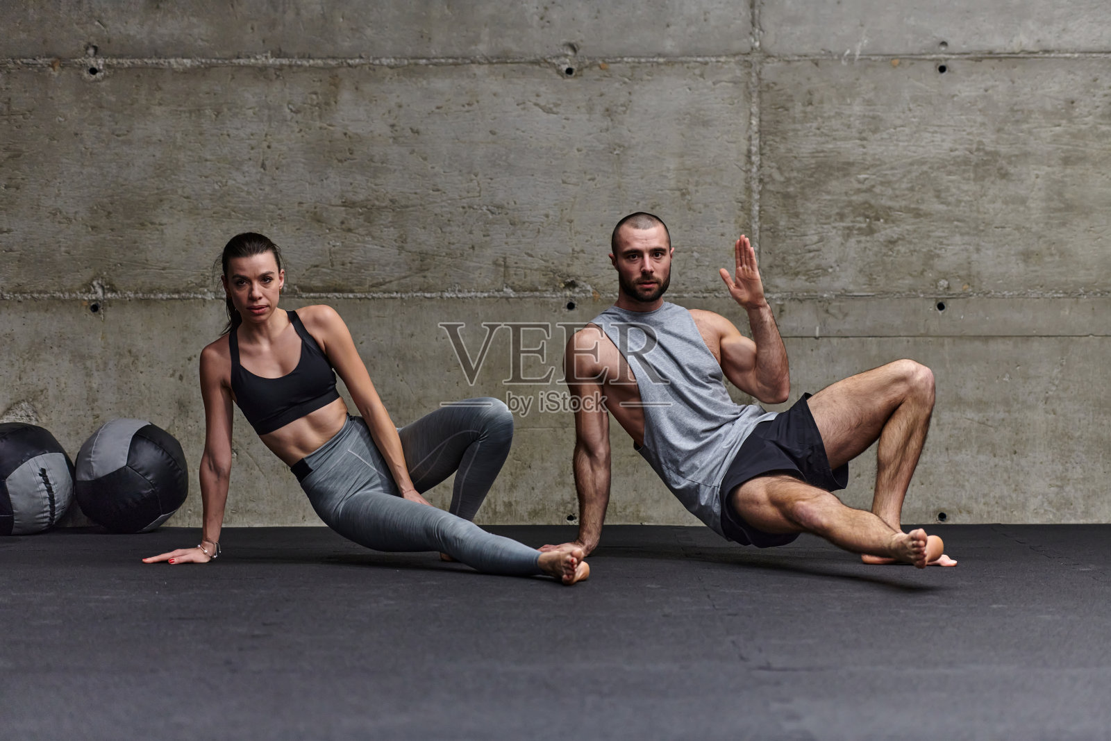 一对有魅力的夫妇在健身房一起做各种伸展运动，展示他们对健身、柔韧性和整体健康的奉献精神。与同步的动作，他们展示协调，平衡和耐力，同时支持照片摄影图片
