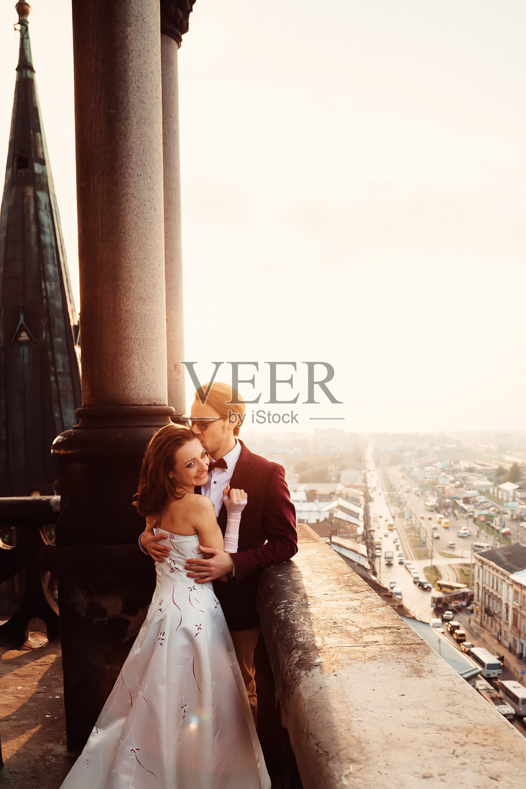 新郎在阳台上拥抱并温柔地亲吻她的妻子照片摄影图片