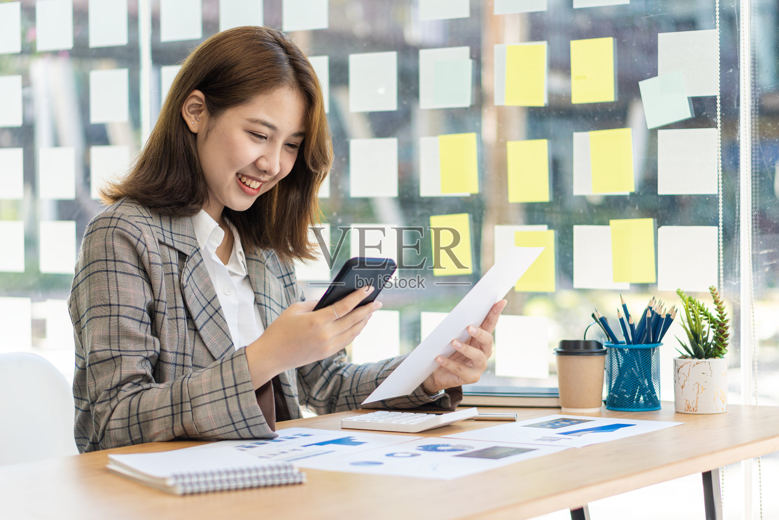 亚洲女性，个体户，专注于带笔记本电脑的手机。财务分析，图表，账目，图表，在线营销计划，基于户外咖啡店的工作理念。照片摄影图片