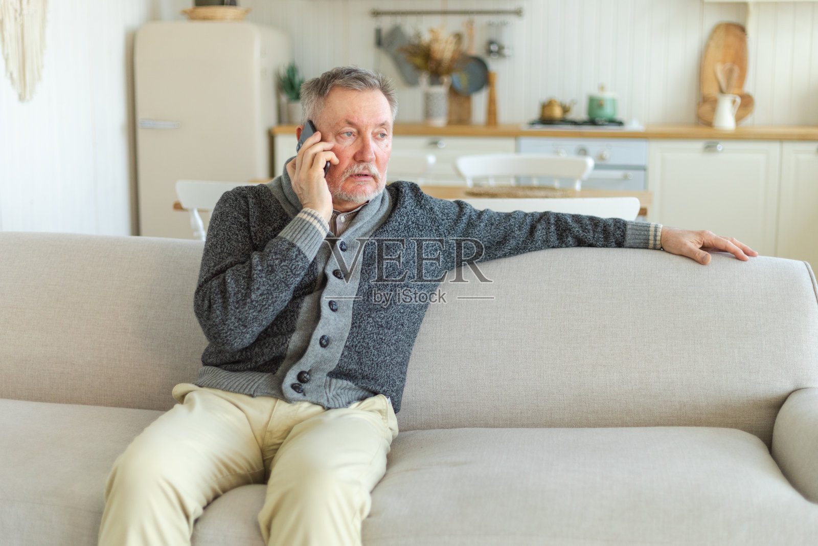 快乐的中年老人和家人朋友用智能手机聊天。老爷爷拿着手机和长大的孩子们聊天，在家里休息。老一辈人使用现代科技。照片摄影图片