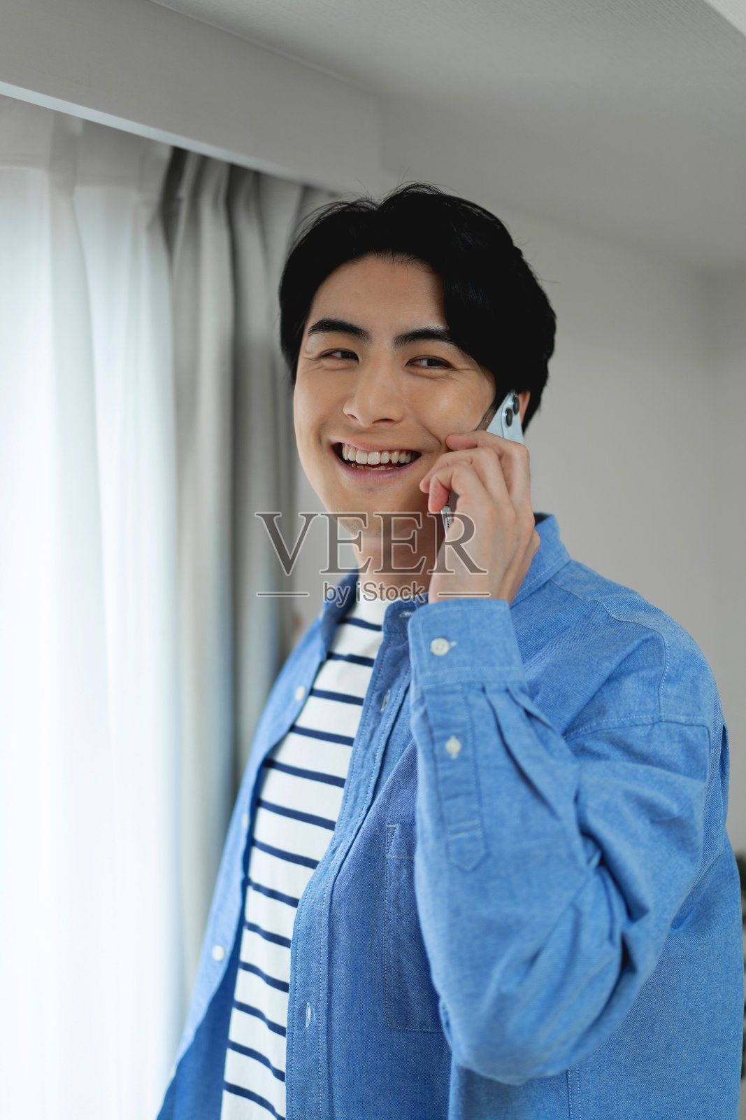 一个日本人站在窗边打电话照片摄影图片