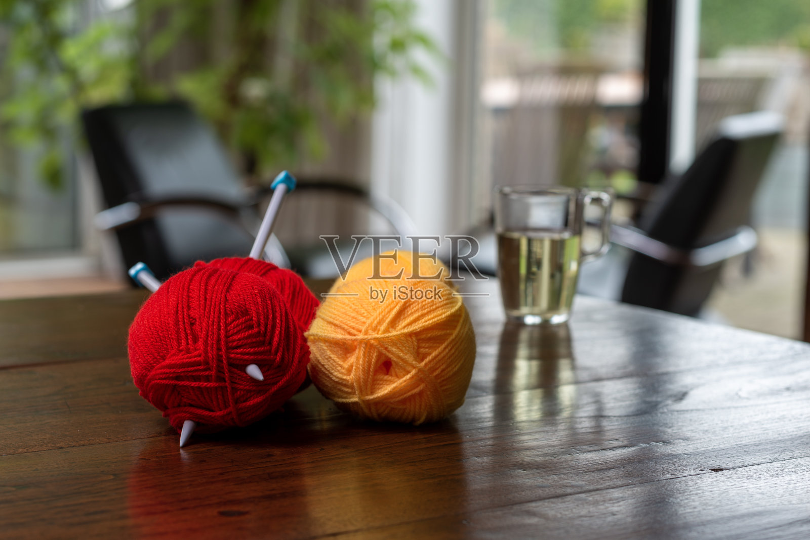 微距拍摄的红绿黄羊毛球和两根针织针。照片摄影图片