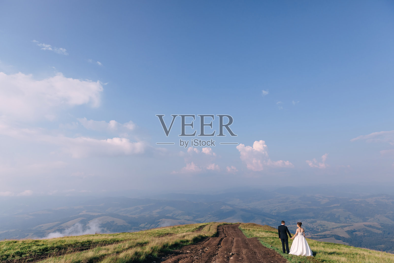 新婚夫妇走在田野里，风景优美。新娘和新郎照片摄影图片