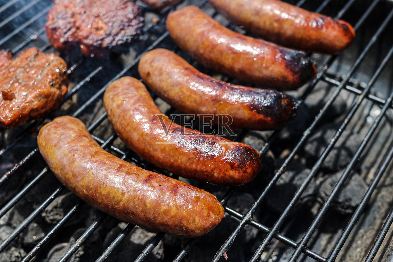 猪肉香肠和汉堡放在木炭烤架上照片摄影图片