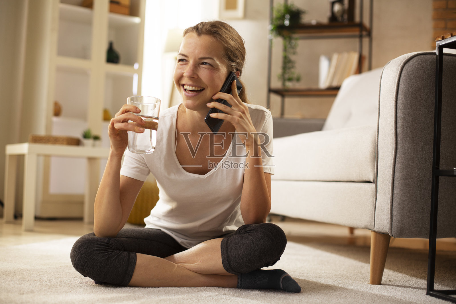 美丽的女人一边在家玩手机一边享受。照片摄影图片