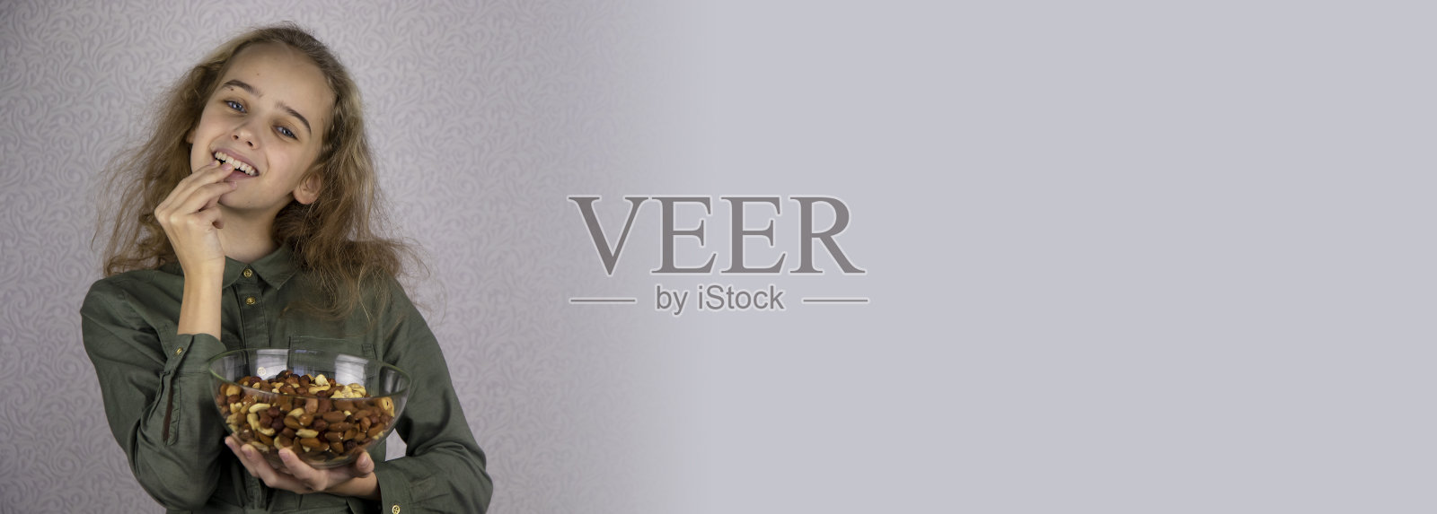 美味又健康的食物。一个十几岁的女孩手里拿着一个透明的碗，里面装着有机坚果。完全和适当营养的概念照片摄影图片