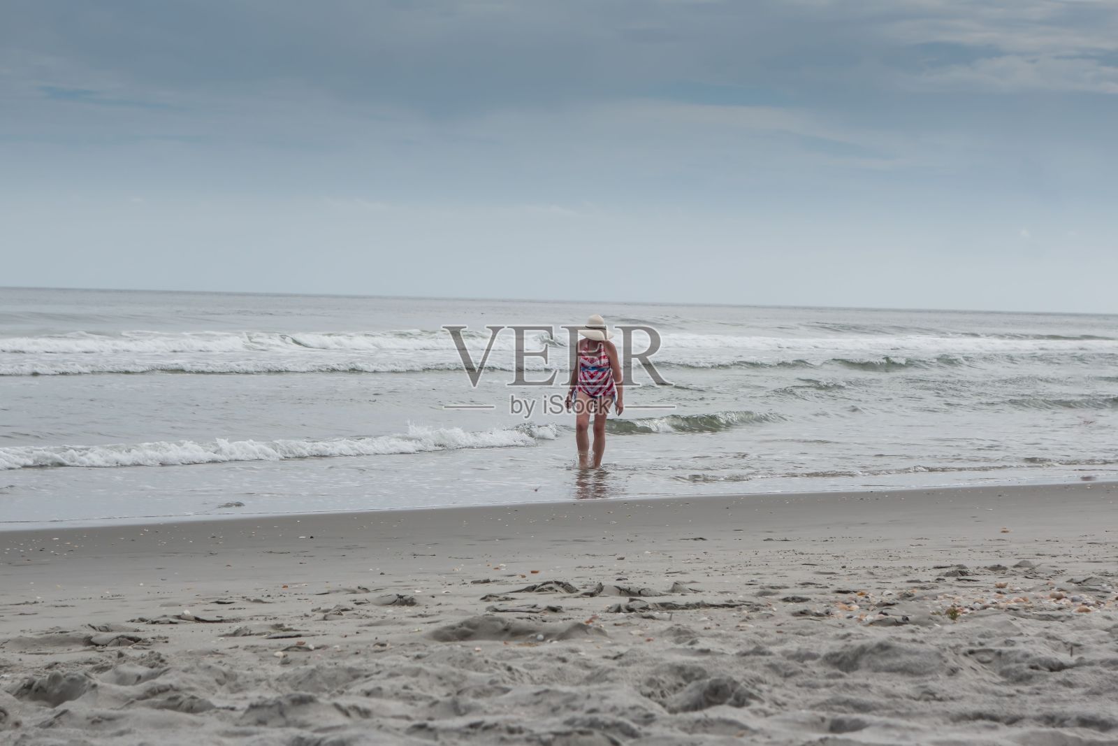 夏天的一天，一名女子在南卡罗来纳州默特尔海滩的海浪中散步照片摄影图片