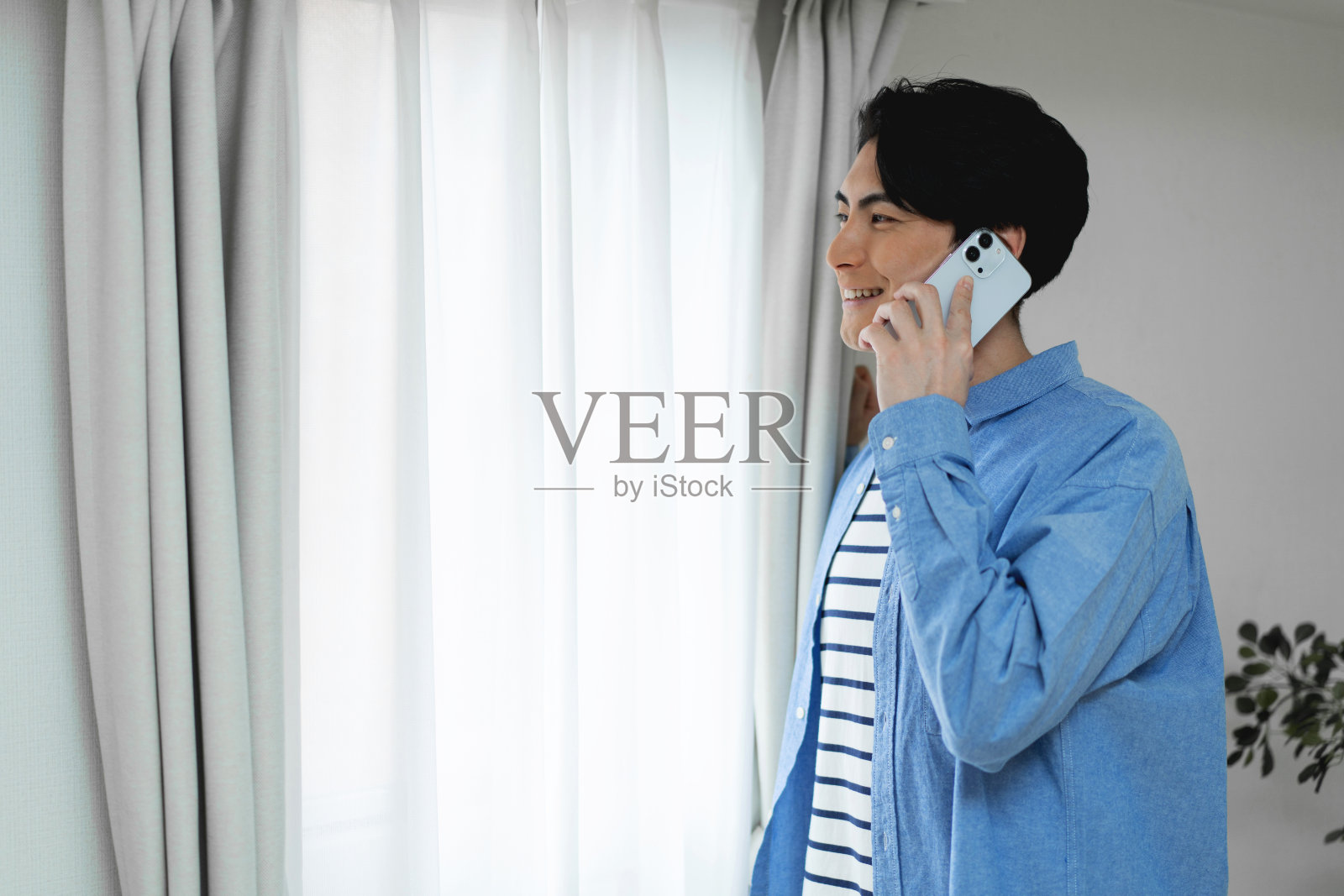 一个日本人站在窗边打电话照片摄影图片