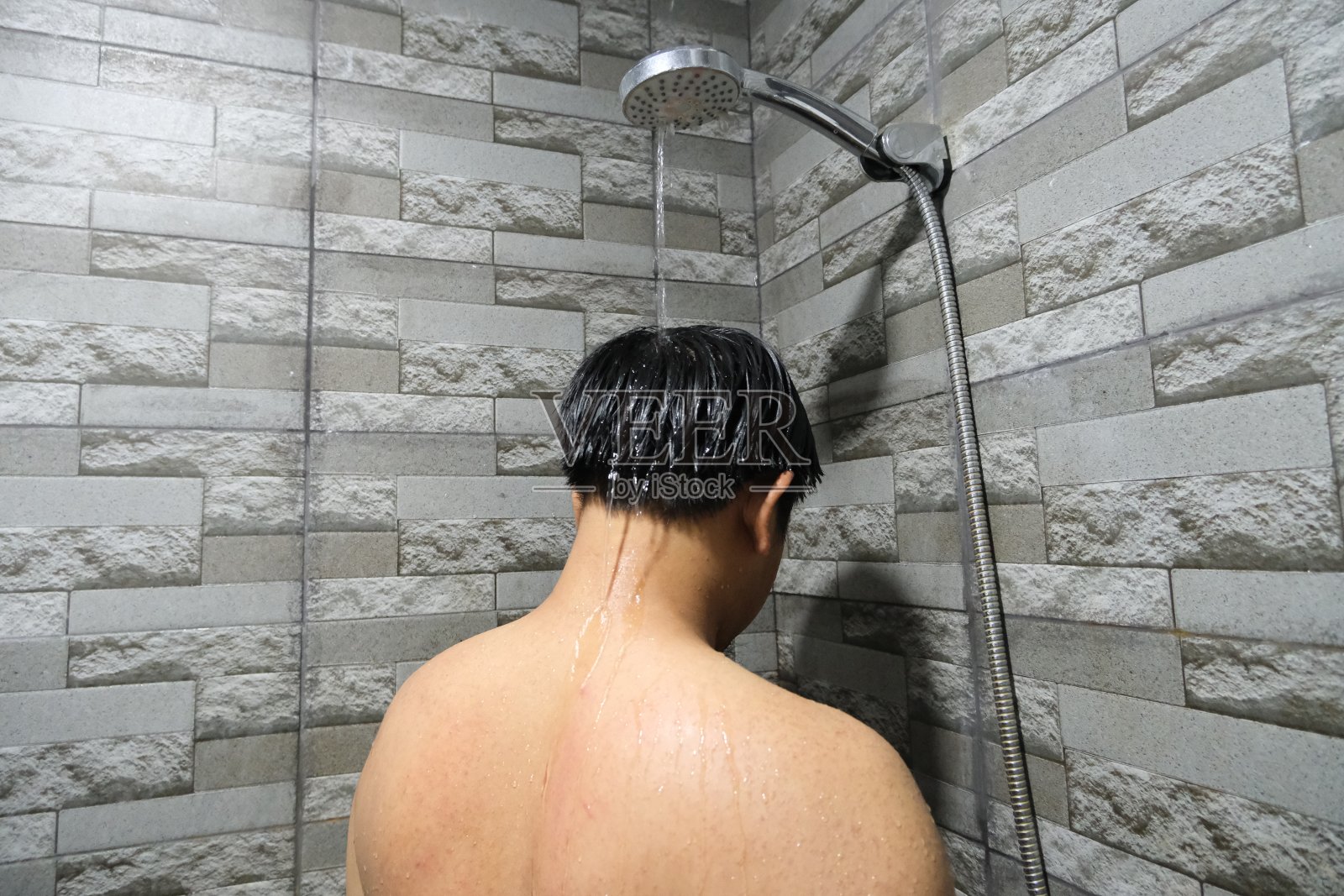 从背后看一名印尼男子正在洗澡照片摄影图片