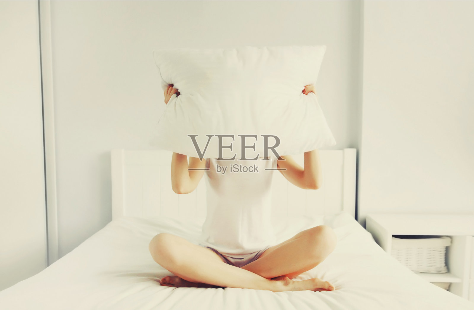 健康的睡眠，睡意朦胧的失眠妇女用枕头盖着头躺在柔软舒适的床上，白色的卧室照片摄影图片