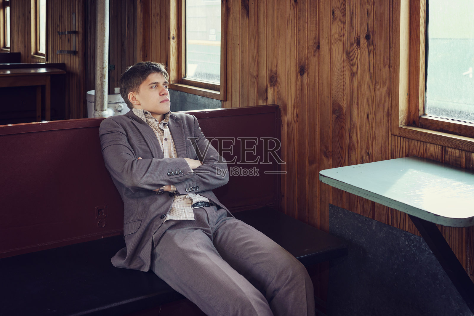 一个年轻人坐在一节老式的火车车厢里，一边看书，一边望着窗外照片摄影图片