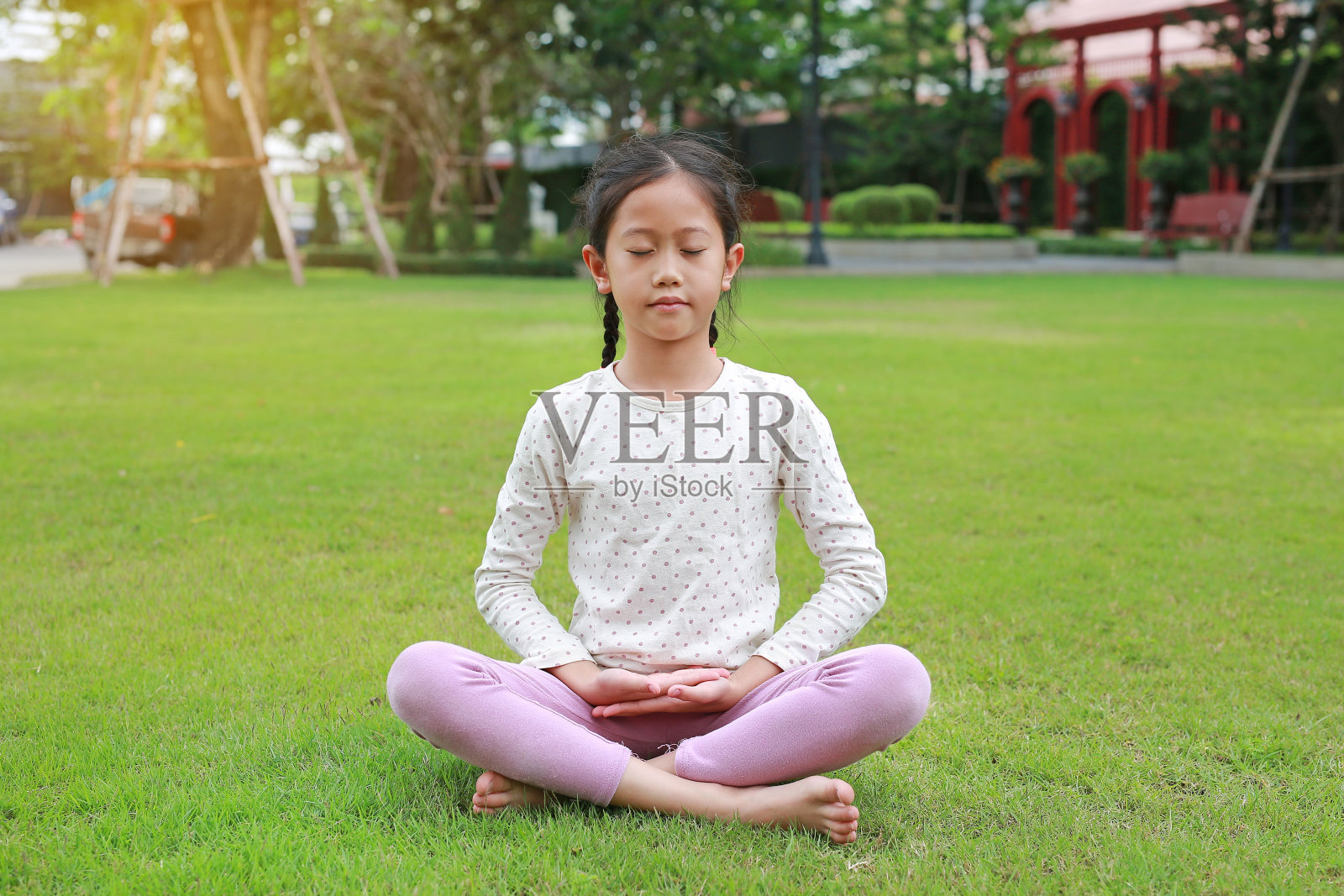 亚洲女孩坐在花园的绿草地上练习正念冥想的肖像。和平的概念。照片摄影图片