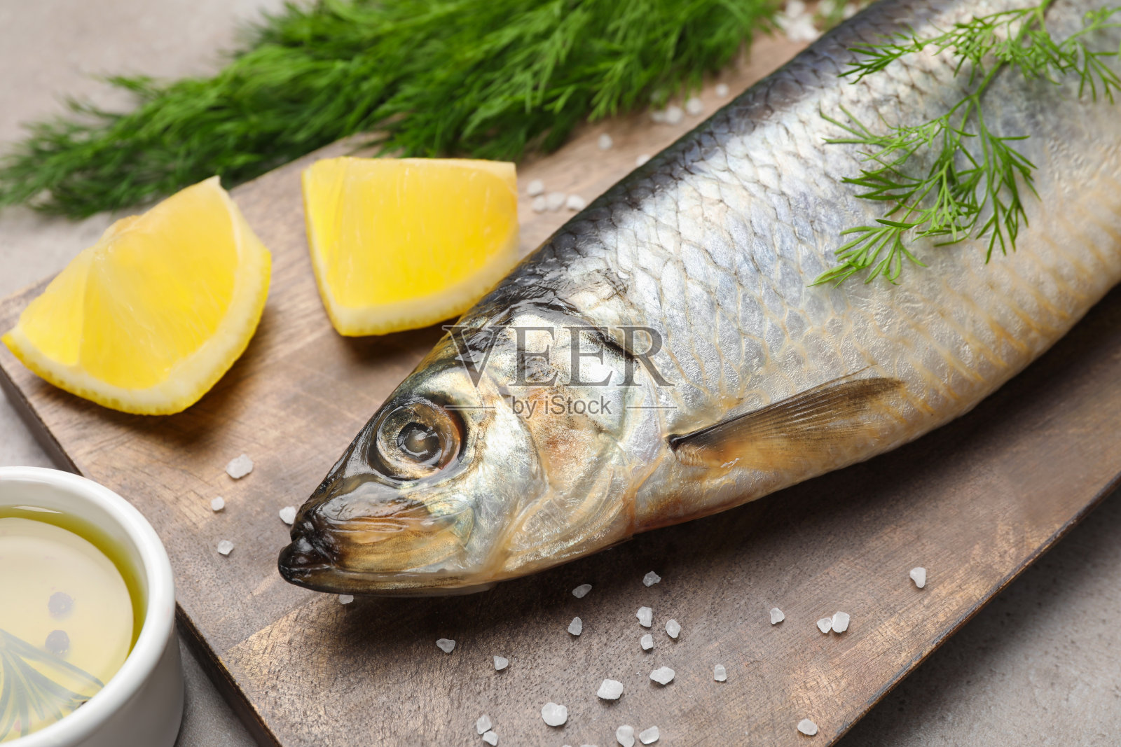 灰色的餐桌上，配上美味的咸鱼、莳萝、柠檬和橄榄油，特写照片摄影图片