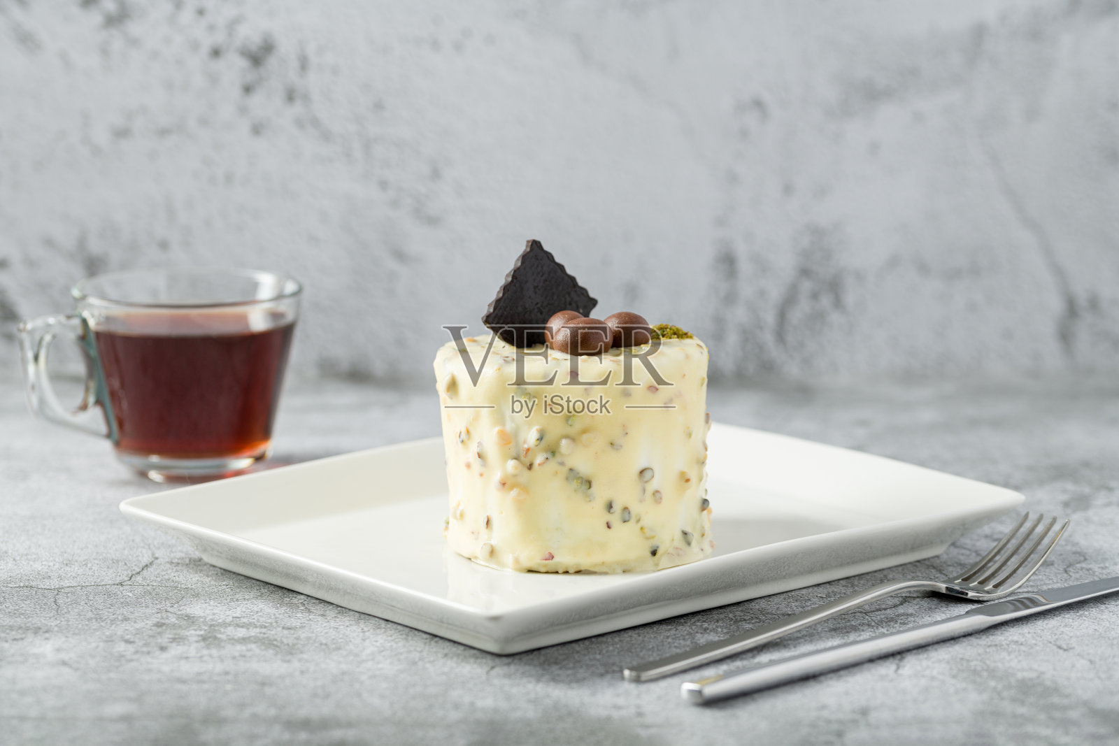 单人迷你蛋糕，白色瓷盘上有开心果和白巧克力照片摄影图片