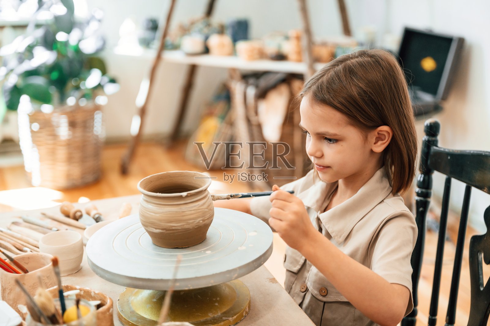 用刷子刷锅。小女孩正在作坊里学习制作陶器照片摄影图片