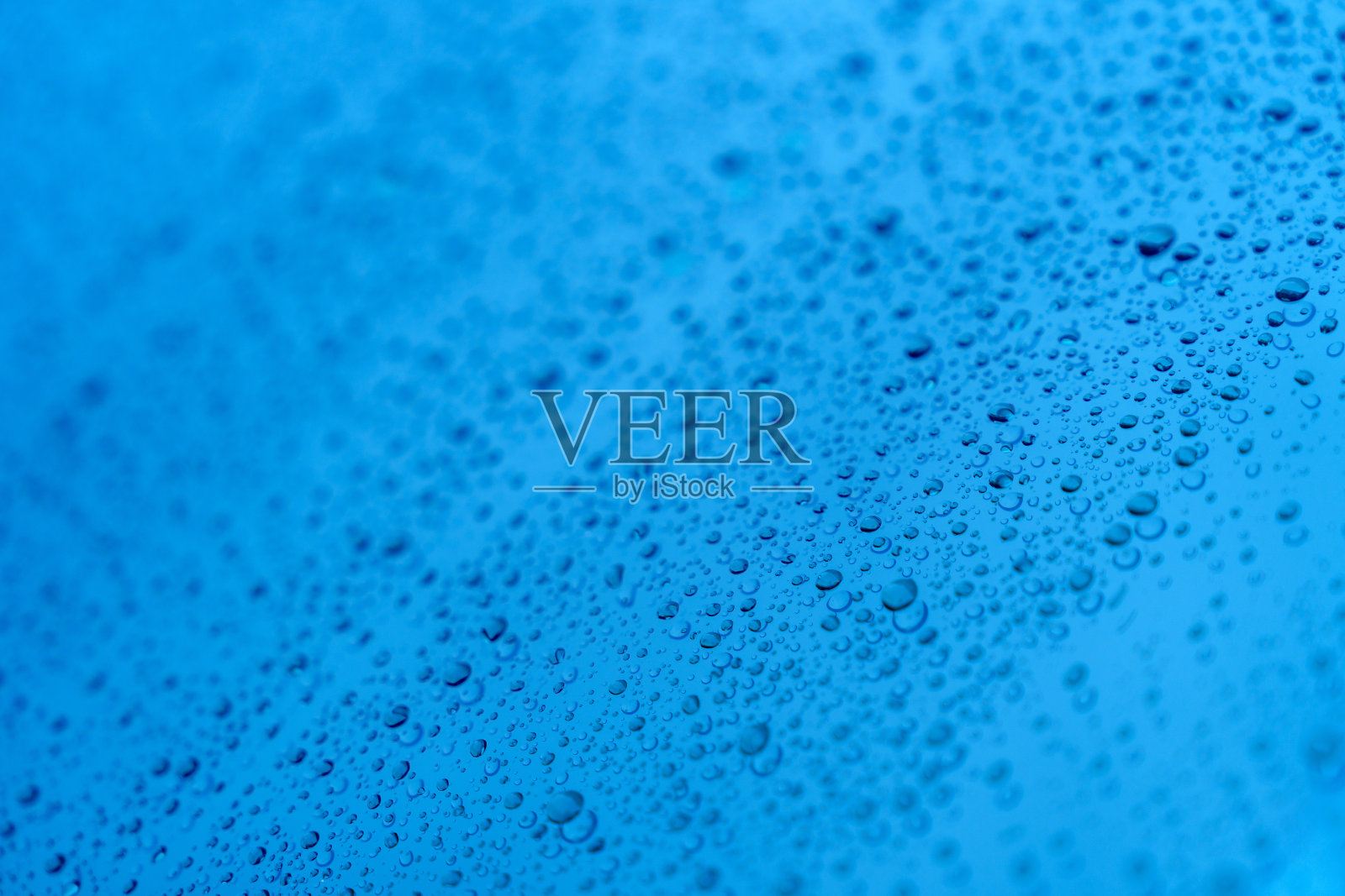 一幅完整的画面捕捉了蓝色背景上水滴形成的纹理照片摄影图片