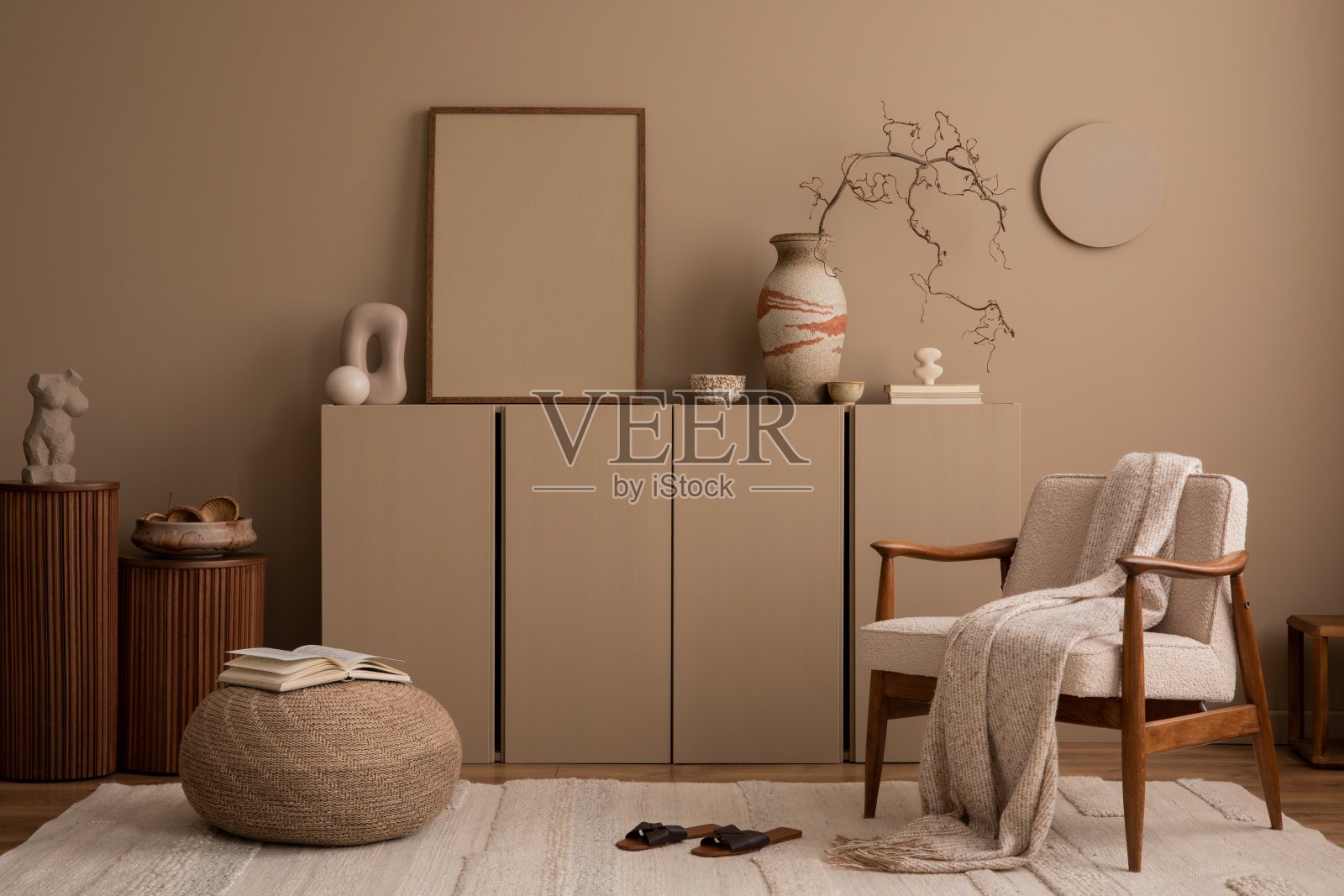 客厅内部的美学构成，模拟海报框架，棕色墙壁，餐具柜，圆形扶手椅，雕塑，编织靠垫，格纹和个人配件。家居装饰。模板。照片摄影图片