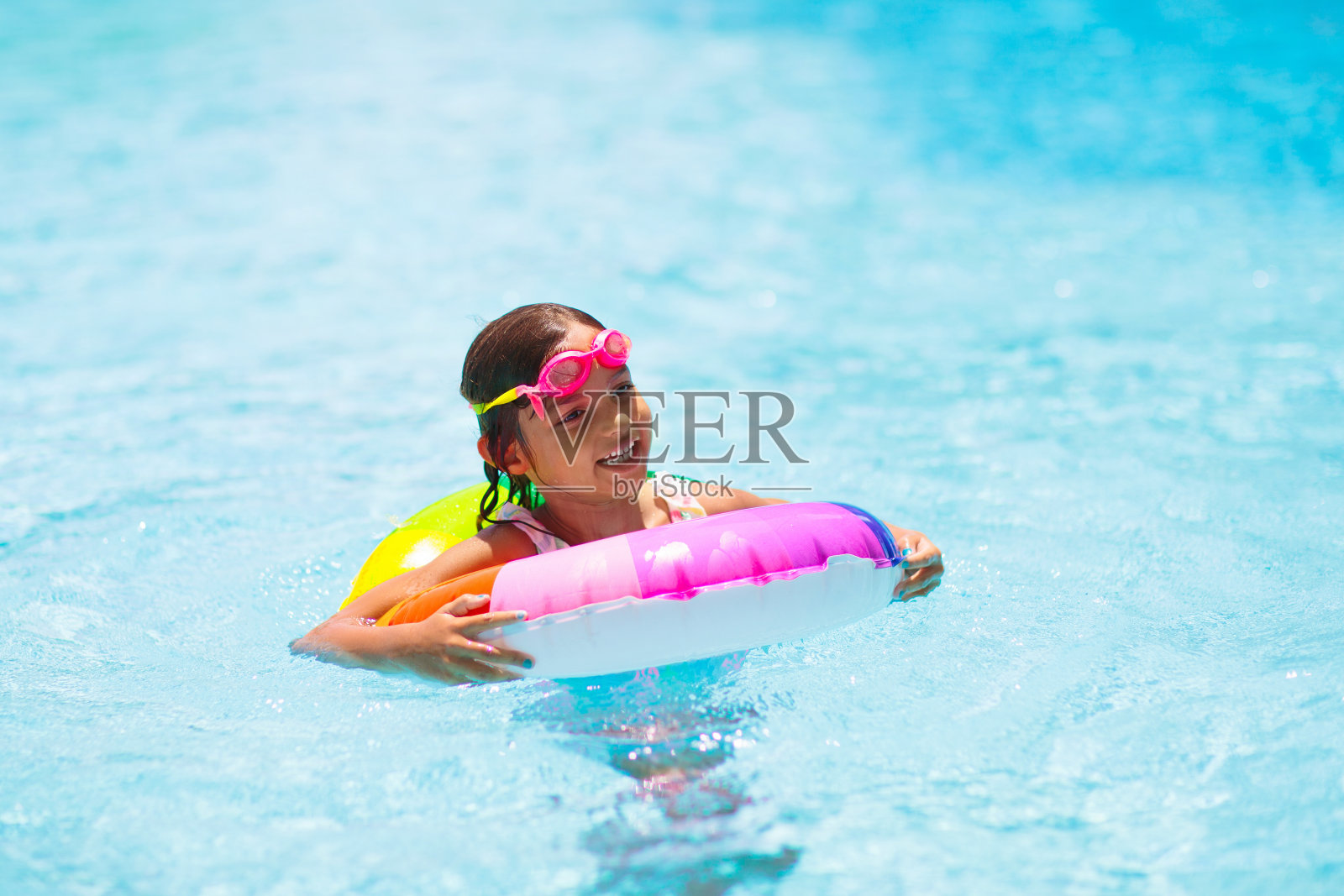 孩子在游泳池的玩具环上。孩子们游泳。照片摄影图片