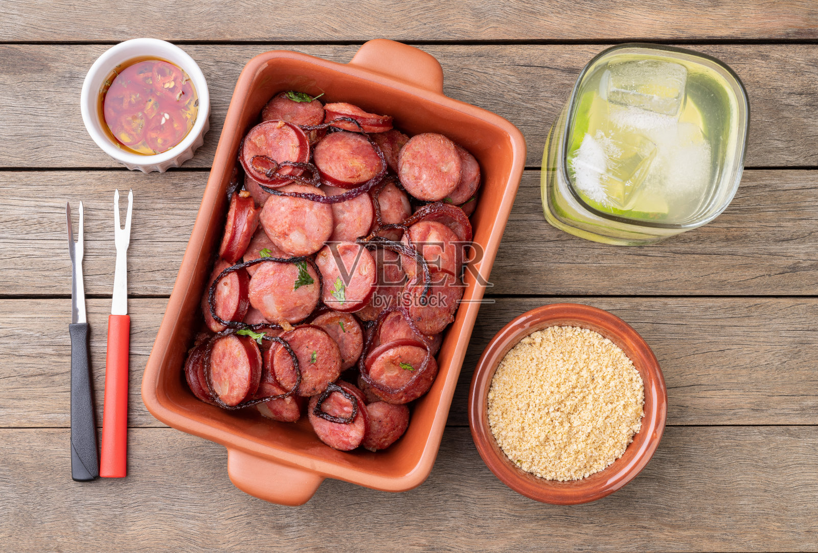 木桌上烤焦莴苣香肠配洋葱、法罗法和凯皮林纳酒照片摄影图片