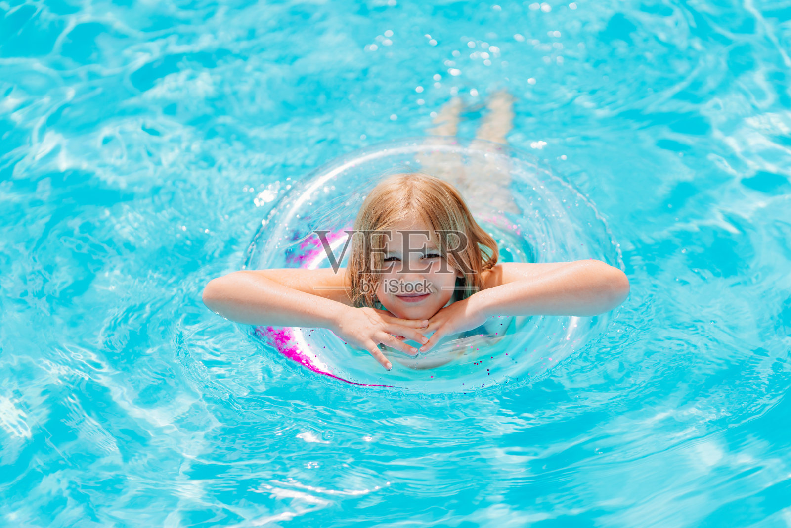 可爱有趣的十几岁的女孩穿着泳衣，带着充气救生圈在游泳池里游泳照片摄影图片