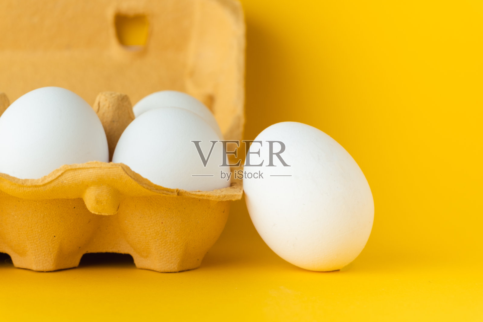 白色鸡蛋的特写镜头在纸盒棕色盒子在黄色的背景。微距镜头。为自由文本复制空间。照片摄影图片
