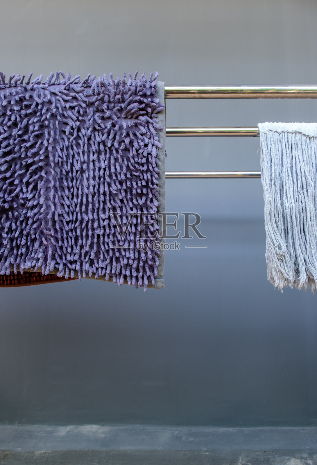 清洁脚刮板和拖布挂在金属线上。照片摄影图片