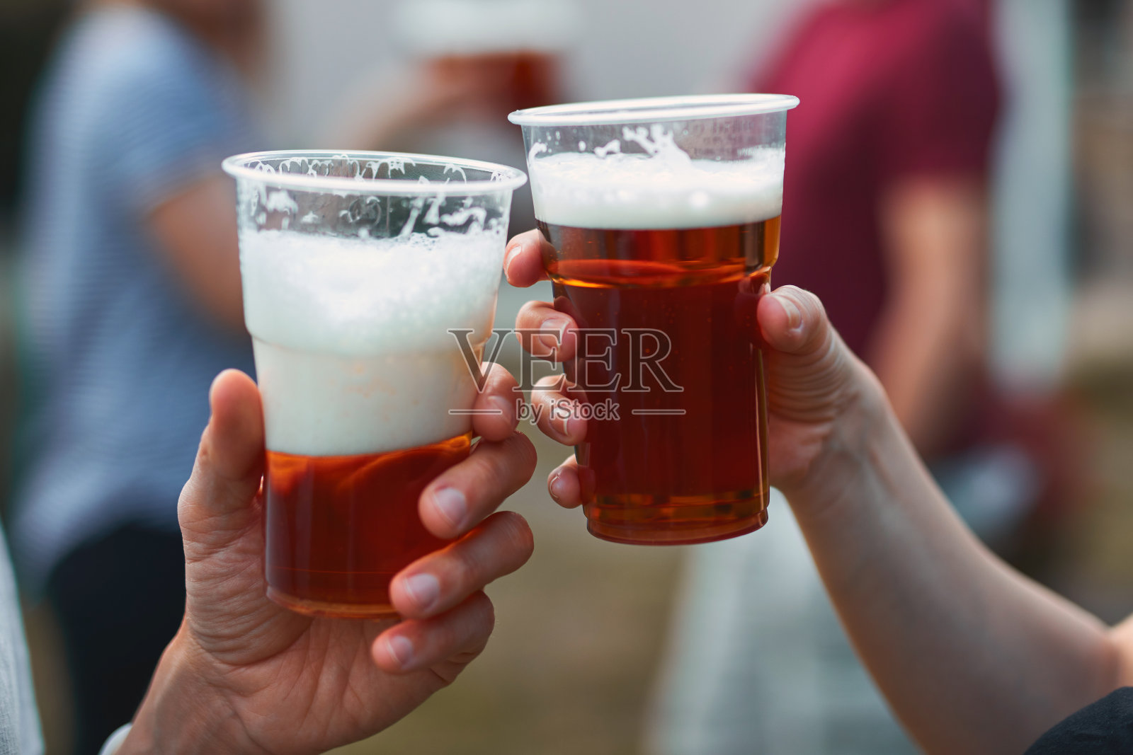 人们拿着啤酒杯，享受着夏日的户外时光。照片摄影图片