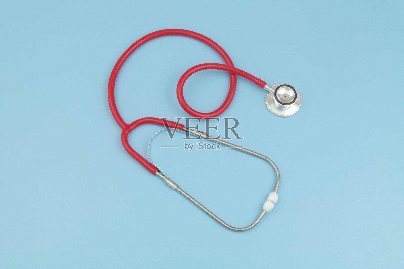蓝色背景上的红色听诊器照片摄影图片