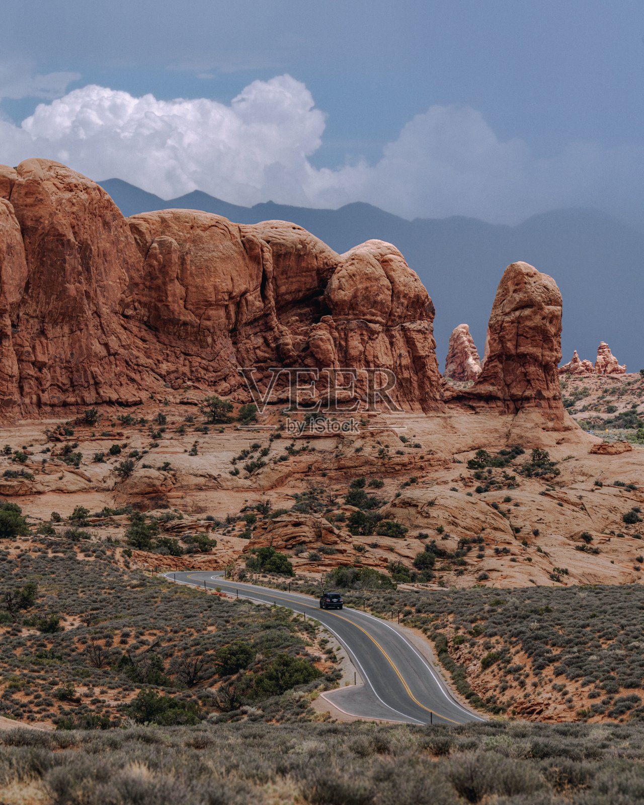 在黑暗的天空下，沙漠中被岩石包围的道路照片摄影图片