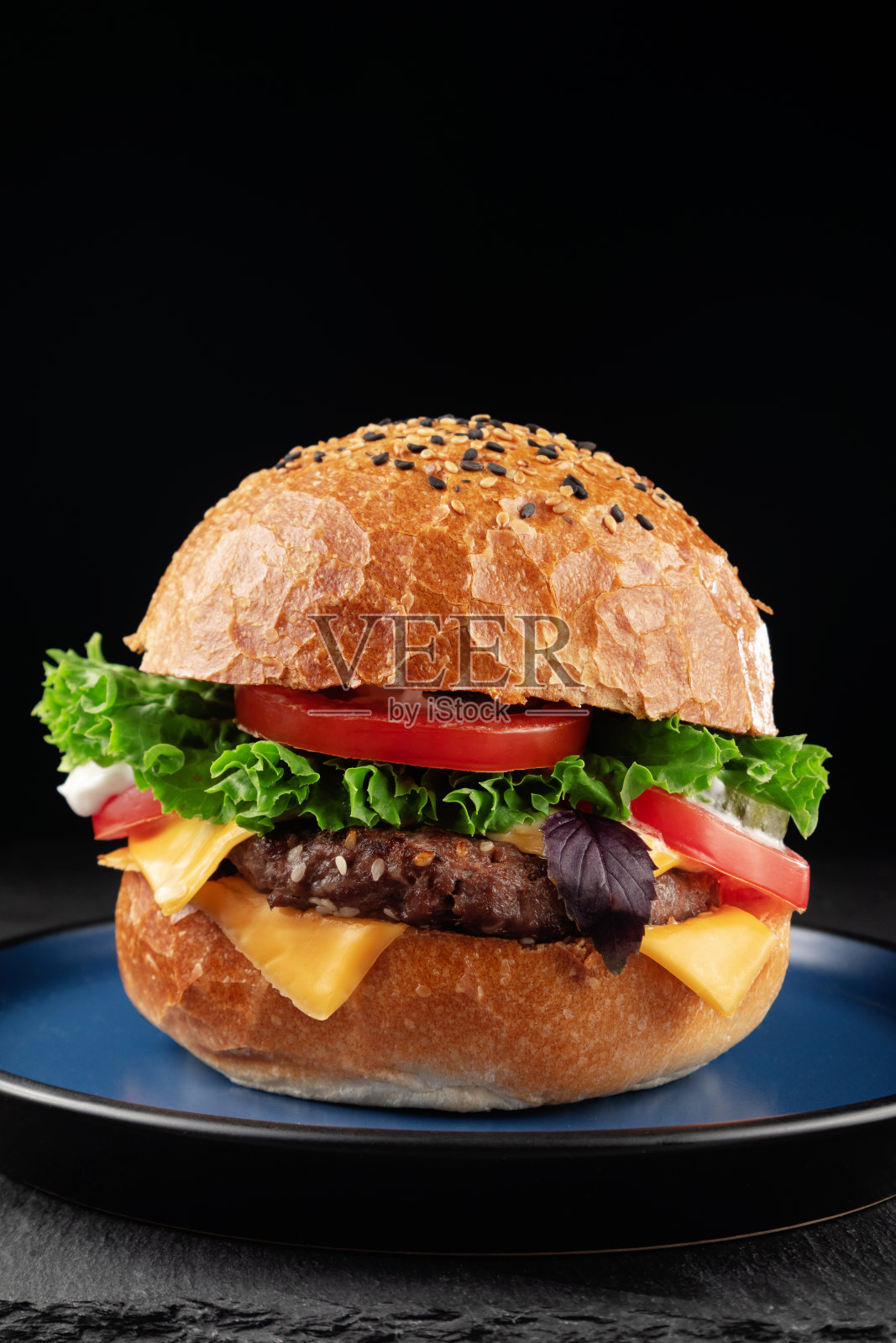 黑色背景的奶酪、生菜和西红柿汉堡包。照片摄影图片